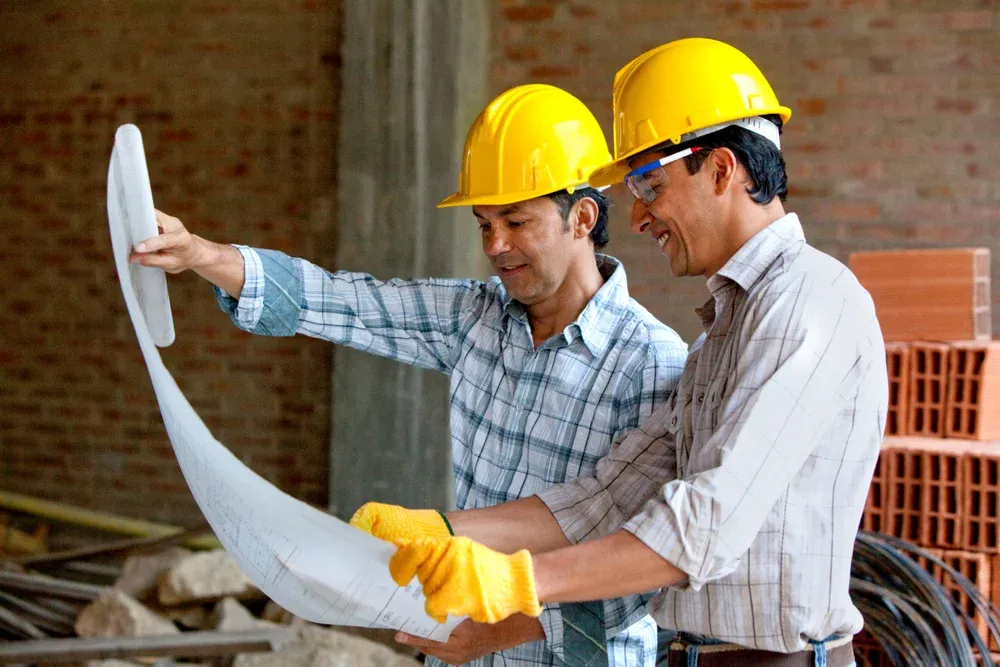imgi_1_Architects-at-a-construction-site-looking-at-blueprints contractors looking to a blueprint or plan