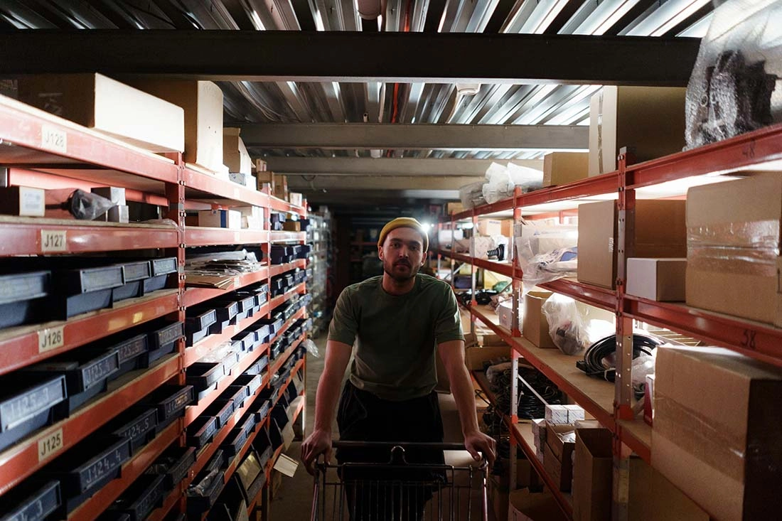 pexels-cottonbro-7019319-compressed A man walks through a spacious warehouse, surrounded by shelves filled with various items