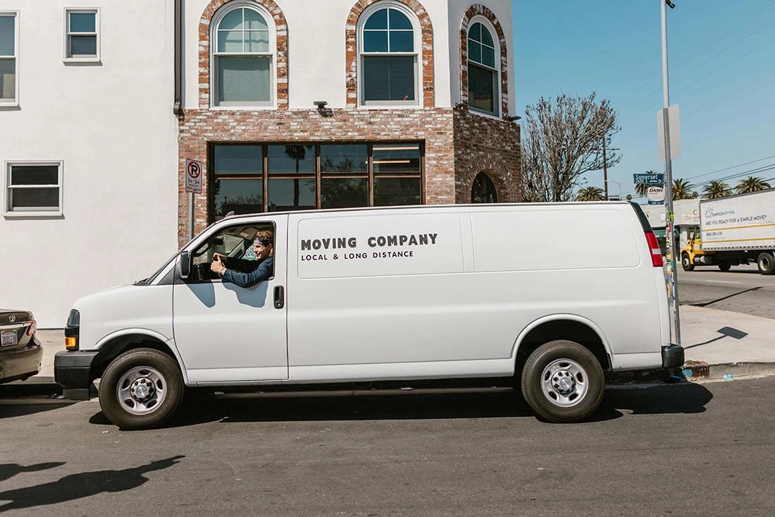 pexels-rdne-7464398-compressed A white company van is parked outside a building, with its logo visible on the side, under bright daylight